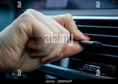 Finger einer weiblichen Hand halten und bewegen den Einstellhebel der Luftkanalklappe im Innenraum eines modernen Autos. Nahaufnahme, Weichzeichnung, Unschärfe Stockfoto