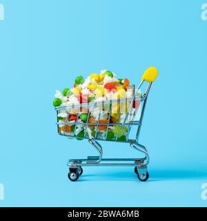 Gefrorenes Gemüse in Spielzeug-Warenkorb auf blauem Hintergrund sortiert. Voll von verschiedenen gefrorenen Gemüse Lebensmittel-Shop Trolley. Quadratisches Zuschneiden Stockfoto