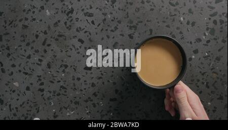 Nehmen Sie Tasse mit Kaffee in schwarzer Tasse auf Beton Hintergrund Draufsicht Stockfoto