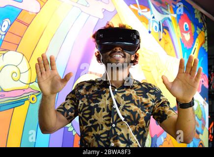 Der dunkelhäutige fröhliche Kerl tauchte in die virtuelle Welt, trug Virtual-Reality-Brille. Porträt eines positiven afroamerikaners mit Afro Stockfoto