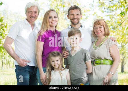 Familienporträt für mehrere Generationen im Freien. Glückliche Eltern mit zwei Kindern und Großeltern im Sommerpark Stockfoto