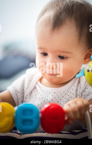 Ein Jahr altes Baby sitzt im Wanderer mit bunten pädagogischen addons. Stockfoto