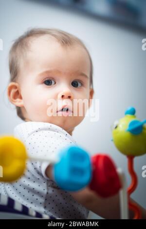 Ein Jahr altes Baby sitzt im Wanderer mit bunten pädagogischen addons. Stockfoto