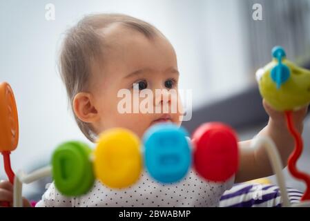 Ein Jahr altes Baby sitzt im Wanderer mit bunten pädagogischen addons. Stockfoto