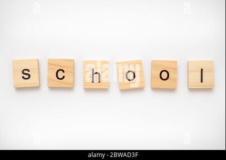 Hölzerne Buchstabenkacheln, die das Wort SCHULE buchstabieren Stockfoto