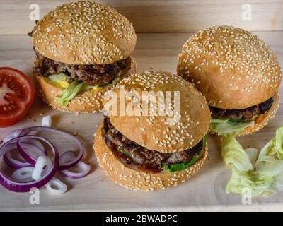 Drei frische Burger lag auf dem Board mit Gemüse Stockfoto