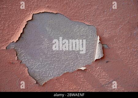 Abgebrochte Farbe auf rauer Stuckwandstruktur. Fassadenrelief lachsfarben gestrichen. Stockfoto