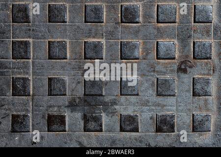 Quadratischer Abwasserkanal, strukturierter Boden neben einem Abfluss