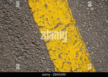 Textur einer abgenutzten gelben Linie auf einer Asphaltstraße. Nahaufnahme. Draufsicht. Stockfoto