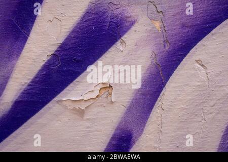 Lila und weiß rissige Wand mit abgebrochener Farbe. Nahaufnahme einer Graffiti-Textur. Street Art Hintergrund. Stockfoto