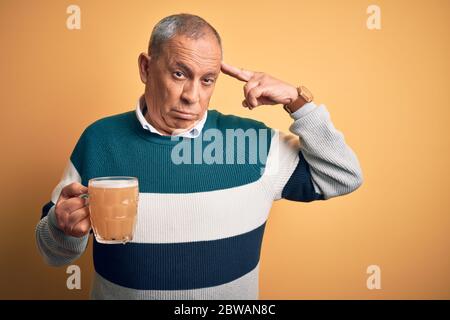 Senior stattlichen Mann trinken Glas Bier über isolierten gelben Hintergrund Shooting und Tötung sich Zeigen Hand und Finger zu Kopf wie Stockfoto