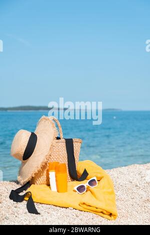 Decke mit Strohhut und Tasche Sonnenschutz Hautpflege Lotion am Meer Sommerstrand Stockfoto