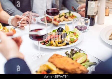 Nahaufnahme von italienischem Essen auf dem Tisch im Restaurant mit Leuten, die essen Stockfoto