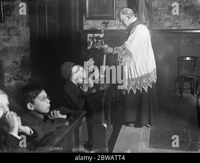 Der Segen von St Blaise, die Candlemass-Zeremonie in St Etheldreda ' s Kirche, Holborn, London. Pater Rob, der die Zeremonie am 2. Februar 1933 leitete Stockfoto