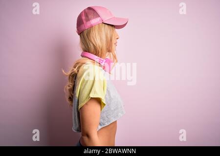 Junge schöne blonde Sportlerin Sport mit Kopfhörer über rosa Hintergrund suchen zur Seite, entspannen Profil Pose mit natürlichen Gesicht mit confid Stockfoto
