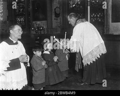 Die "Segnung der Kehlen" der Gemeinde in St Etheldreda ' s Kirche, Ely Place, London. Ein candlemass Tag Zeremonie . Februar 1922 Stockfoto