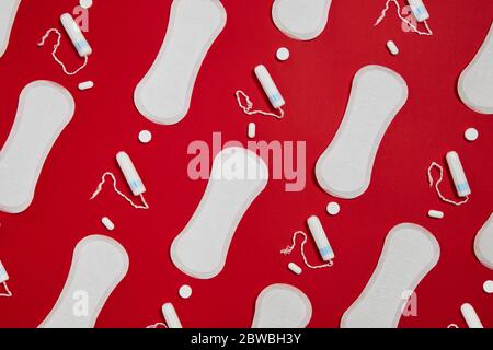 Weiße Damenbinden und Tampons aus reiner Baumwolle auf rotem Hintergrund isoliert. Feminine Hygieneprodukte Stockfoto