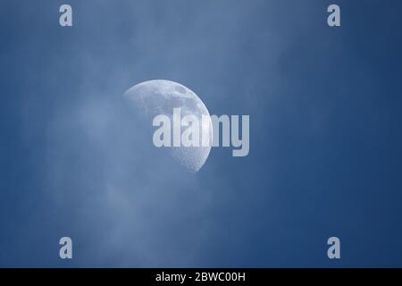 Halbmond, Halbmond im ersten Viertel des Mondes gegen blauen bewölkten Himmel während des Tages Stockfoto