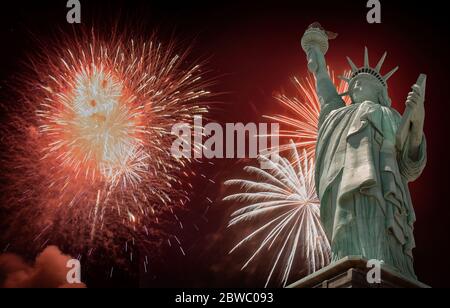 4. Juli Unabhängigkeitstag mit Feuerwerk der Vereinigten Staaten von Amerika in verschiedenen Farben, die gegen eine Freiheitsstatue in der Nacht platzen Stockfoto