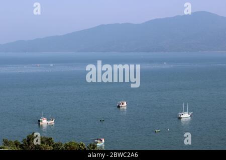 Angelbucht, wo wir mehrere Boote im Vordergrund geparkt sehen, Fischernetze in der Ferne und einen schönen Hintergrund der Berge Stockfoto