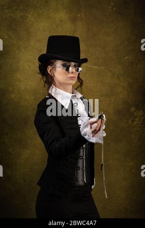 Porträt einer jungen viktorianischen Frau, die einen Hut, eine schwarze Brille, eine Taschenuhr in der Hand trägt Stockfoto