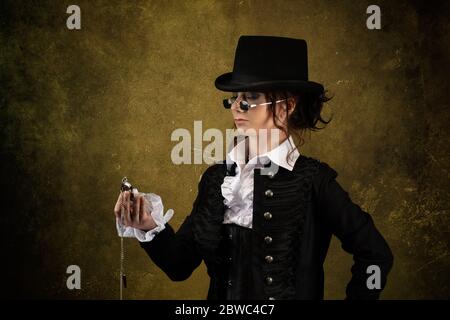 Porträt einer jungen viktorianischen Frau, die einen Hut, eine schwarze Brille, eine Taschenuhr in der Hand trägt Stockfoto