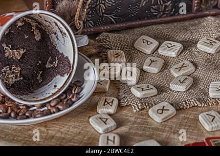 Isoterisches Konzept der Weissagung und Vorhersage. Tarot-Karten, Runen, Kaffeesatz in einer Tasse, Rosenkranz auf einem Tisch vor dem Hintergrund einer alten Brust Stockfoto