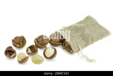 Gruppe von geschälten und ungeschälten Macadamianüssen in Sack auf weißem Hintergrund Stockfoto