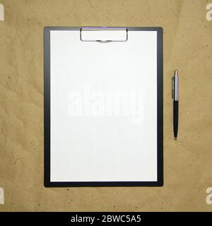 Ein Tablett mit einem weißen Blatt im A4-Format mit Stift auf einem beigen Bastelpapier. Konzept der Analyse, des Studiums, der aufmerksamen Arbeit. Stock Foto mit leerem Platz für Ihren Text und Design. Stockfoto