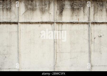 Graue alte Betonwand mit Rissen und rechteckigem Reliefmuster. Konkrete Textur, Raum für Text und Layout für Design. Stockfoto