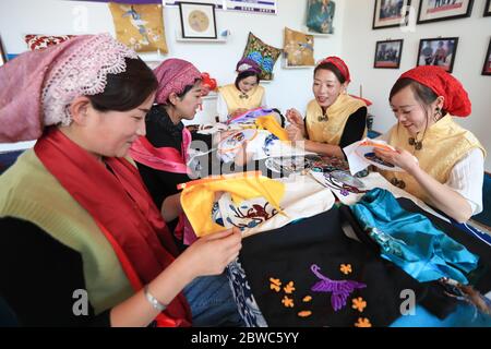 (200531) -- LINXIA, 31. Mai 2020 (Xinhua) -- Ma Semai (2. R) und ihre Kollegen tauschen ihre Stickfähigkeiten bei einem Stickworkshop in der Stadt Daban im autonomen Landkreis Dongxiang, autonome Präfektur Linxia Hui in der nordwestlichen Provinz Gansu, aus, 30. Mai 2020. MA, 36 Jahre alt und aus der Dongxiang-Volksgruppe, ist eine der Stickerinnen, die in einer traditionellen Stickereiwerkstatt arbeitet, die von der lokalen Regierung als Ansatz zur Armutsbekämpfung gegründet wurde. In der Werkstatt waren über 80 Frauen aus der ethnischen Gruppe Dongxiang beschäftigt, die gut in Stickereien sind, und es wurden auch fast 2 Frauen angezogen Stockfoto