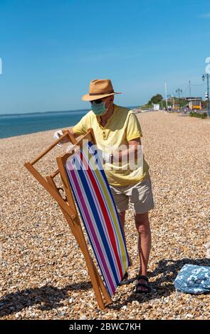 Southsea, Portsmouth, England, Großbritannien. Mai 2020. Älterer Mann, der während des Ausbruchs von Corvid-19 am Strand von Southsea, Großbritannien, einen Liegestuhl öffnete. Stockfoto