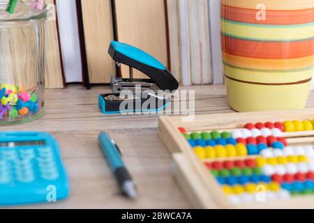 Auf der Tischplatte befinden sich hölzerne Abakus und ein elektronischer blauer Rechner. Stockfoto