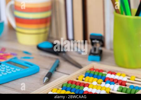 Auf der Tischplatte befinden sich hölzerne Abakus und ein elektronischer blauer Rechner. Stockfoto