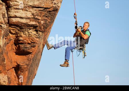 Fotograf und Bergsteiger Norbert Frank fotografiert vor einem Felsen Stockfoto