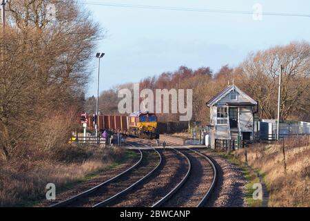 DB Güterbahn der Baureihe 66 Lokomotive 66099 vorbei an der Elsham Signalbox mit einem Güterzug mit Eisenerz Stockfoto