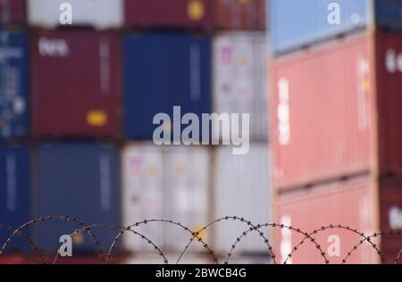 Hinter Stacheldraht stapelte Frachtcontainer an einem belebten europäischen Seehafen Stockfoto