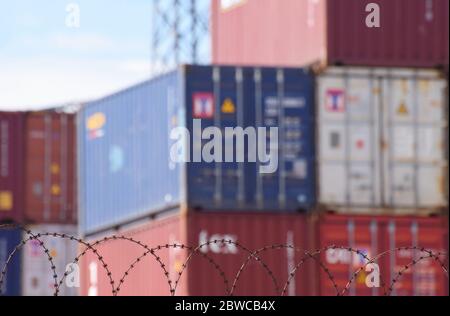 Hinter Stacheldraht stapelte Frachtcontainer an einem belebten europäischen Seehafen Stockfoto