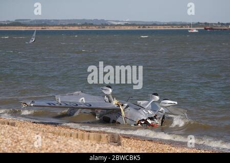 Die Trümmer leichter Flugzeuge wuschen am Strand, nachdem sie in das Meer nahe Calshot Spit stürzten. Zwei Menschen wurden aus dem Flugzeug gerettet. Stockfoto