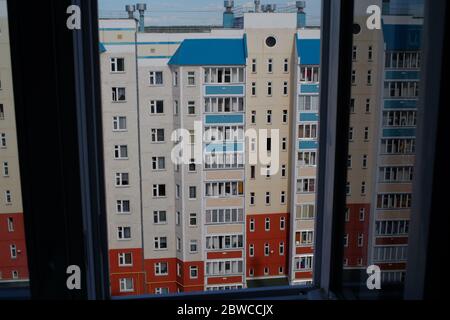 Blick auf ein mehrstöckiges Wohngebäude in der russischen Provinz aus dem Fenster eines Nachbarhauses. Stockfoto