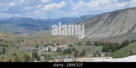 MAMMOTH, WYOMING - 7. JUNI 2017: Mammoth Hot Springs Historic District des Yellowstone National Park im Vordergrund & die Absaroka Mountains dahinter Stockfoto