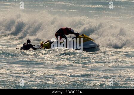 RNLI Rettungsschwimmer retten Surfer am fistral Beach einen Tag nach der Wiederaufnahme des Services am Fistral Beach Cornwall UK Stockfoto