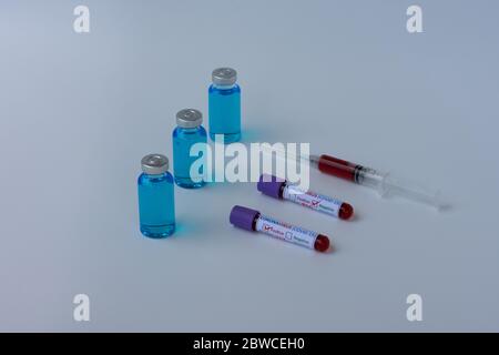 Impfstofffläschchen, Reagenzgläser und eine Spritze, die eine Blutprobe enthält, ein Reagenzglas für die Coronavirus-Analyse (COVID-19). Stockfoto