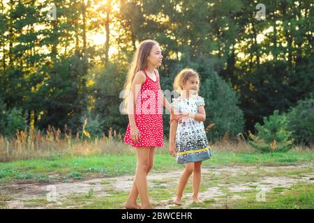 Zwei hübsche kleine Mädchen umarmen und lächeln auf dem Land. Happy Kids Outdoor Konzept Stockfoto