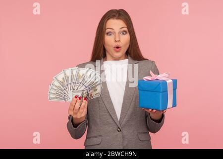 Wow, Geld für Geschenk, Shopping Bonus! Porträt von überrascht elegante Geschäftsfrau in Anzug Jacke hält Geschenkbox und Dollar-Banknoten, Ausdruck einer Stockfoto