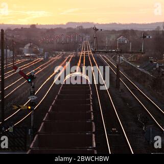 Güterzug mit Eisenerz, der die mechanischen Semaphore-Signale bei Barnetby passiert, während die untergehende Sonne von den Schienen scheint Stockfoto