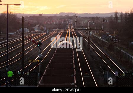 Güterzug mit Eisenerz, der die mechanischen Semaphore-Signale bei Barnetby passiert, während die untergehende Sonne von den Schienen scheint Stockfoto
