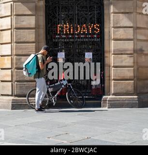 Glasgow, Schottland, Großbritannien. Mai 2020. Ein deliveroo-Lieferradler überprüft sein Handy an einem warmen und sonnigen Sonntagnachmittag außerhalb der TGI Fridays in der Buchanan Street. Die schottische Regierung kündigte am 28. Mai eine Lockerung der Sperrregeln für das Coronavirus an. Kredit: Skully/Alamy Live News Stockfoto