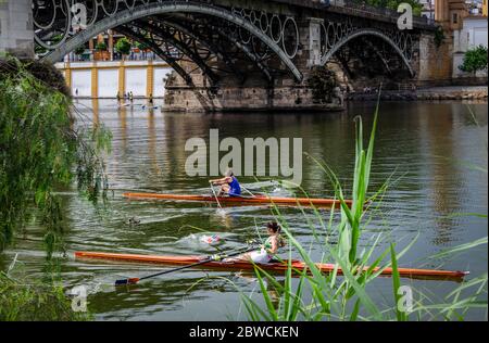 Zwei Frauen rudern im Guadalquivir Fluss unter der Triana Brücke Stockfoto