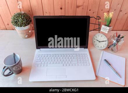 Komfortabler Arbeitsplatz mit Laptop, Tasse Kaffee und Notebook. Stockfoto
